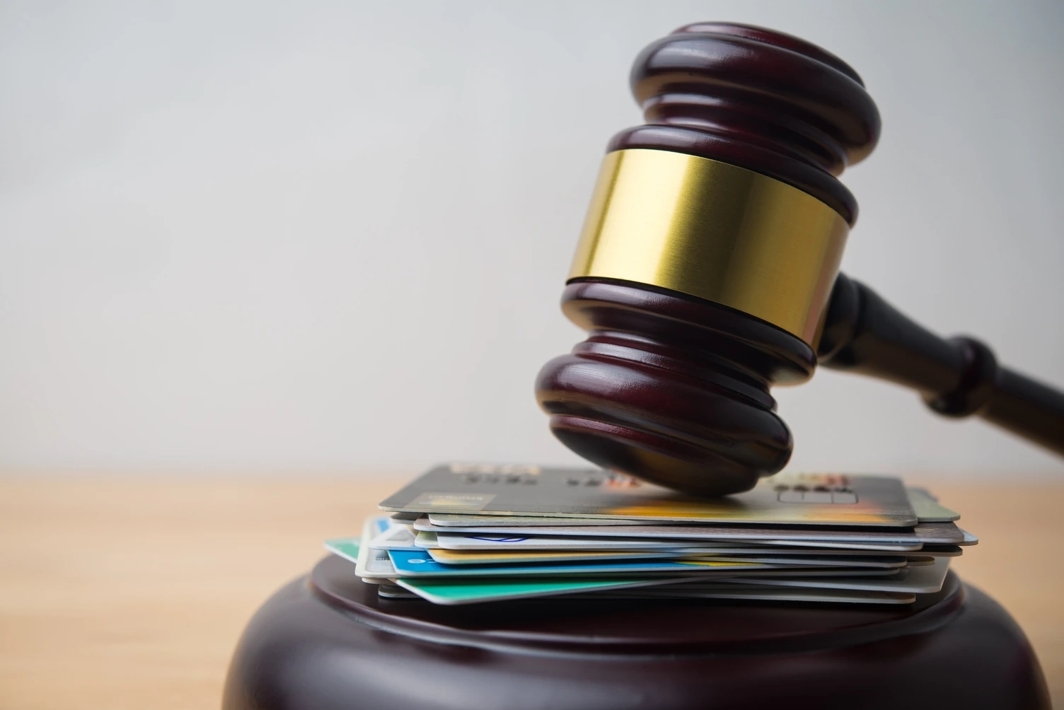 A wooden table displays credit cards alongside a gavel, representing the intersection of finance and law