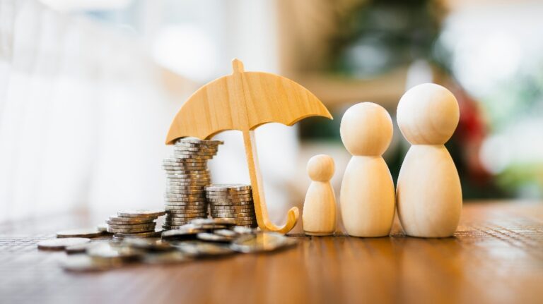 Wooden family figures with coins under umbrella